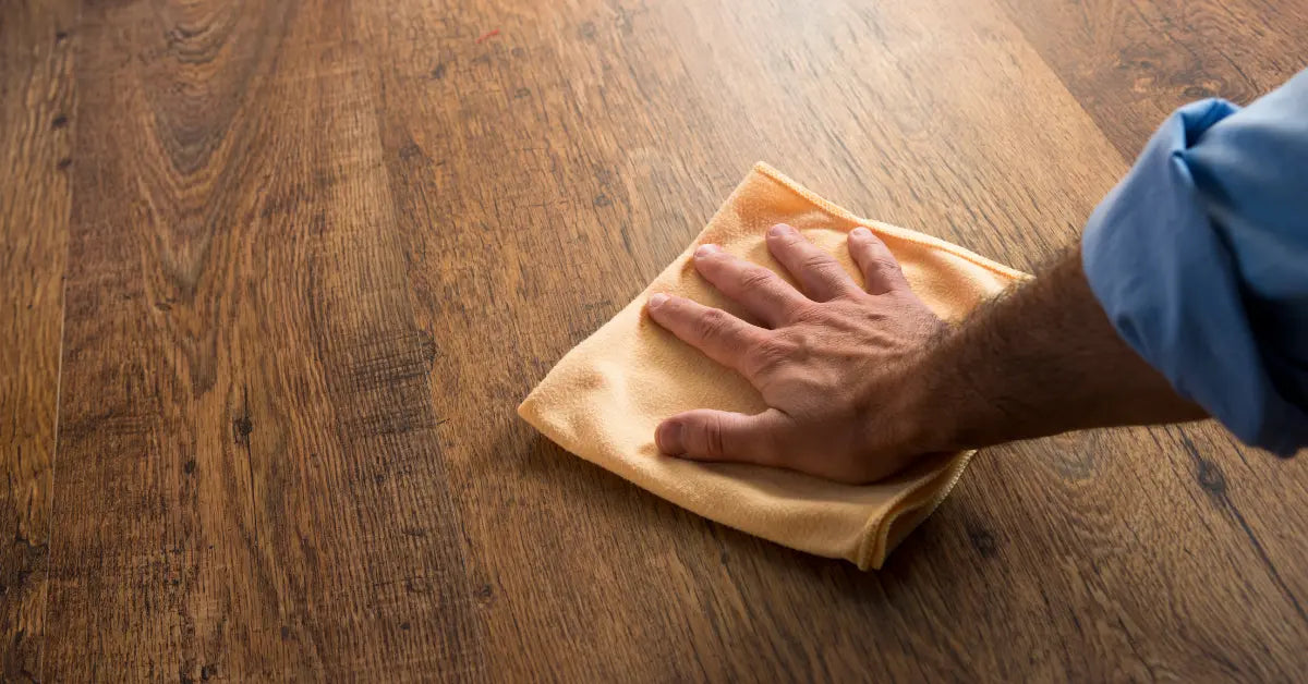 Hand applying wood floor wax with cloth to protect and enhance the shine of wooden flooring