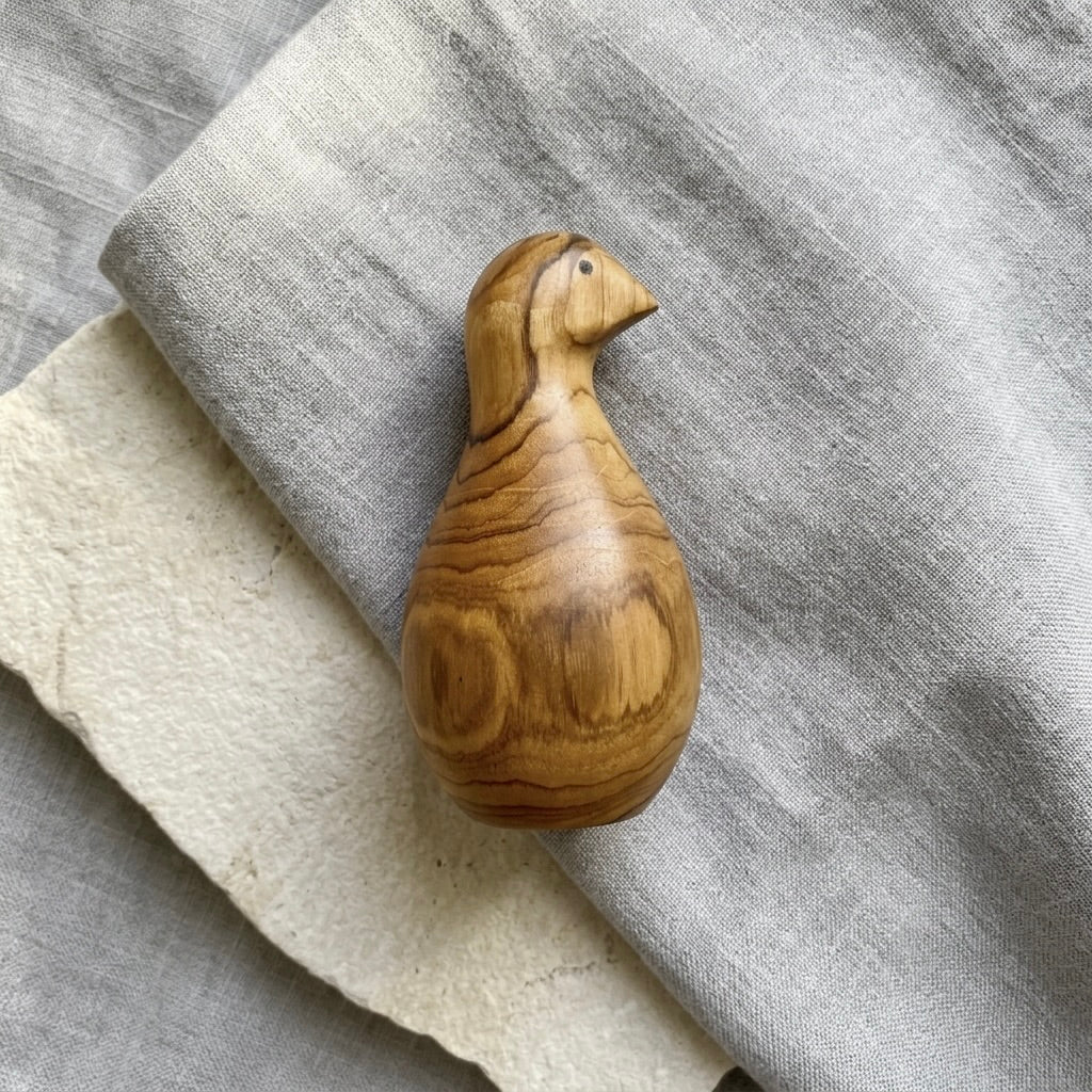 Teak bird sculpture with smooth polished finish and shadow