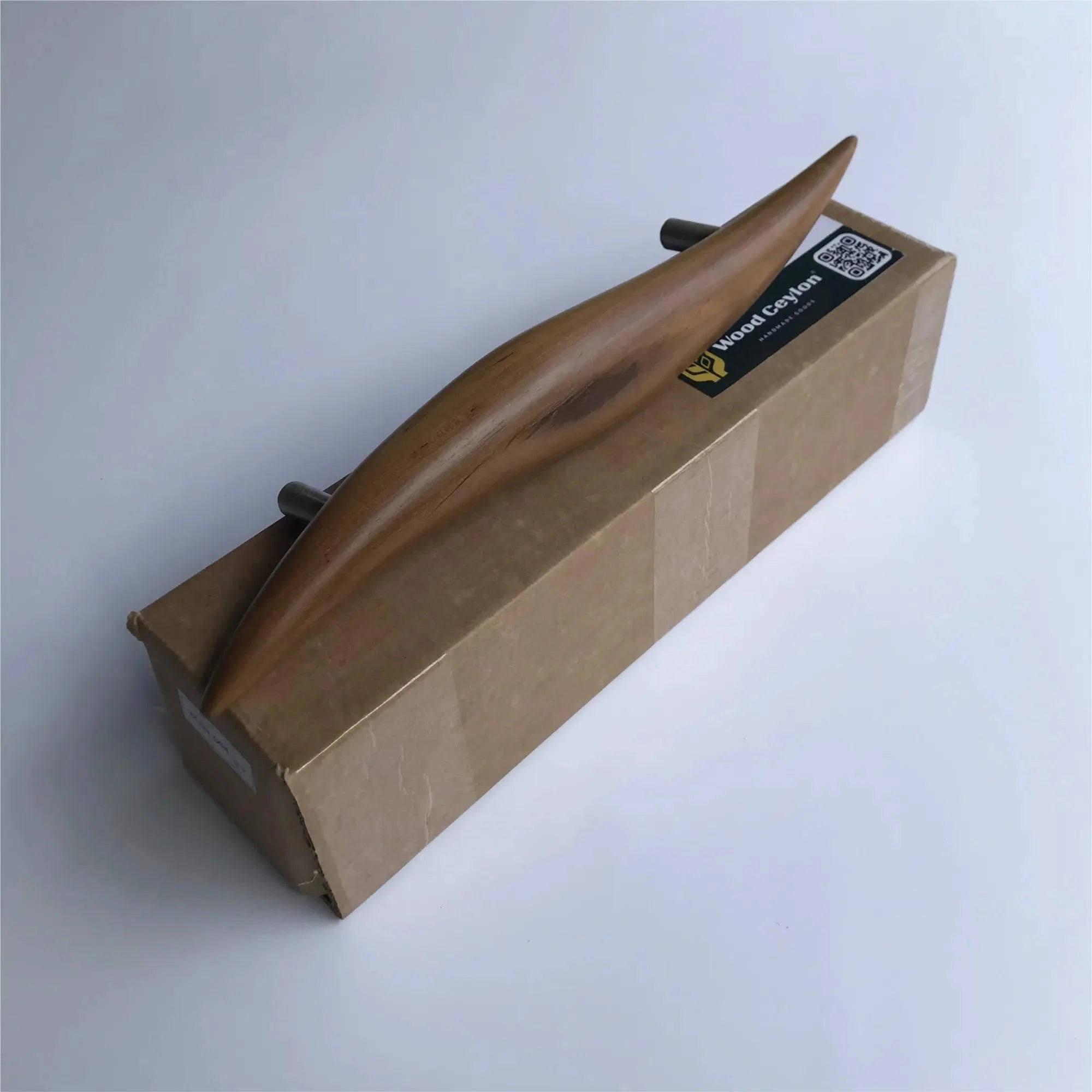 Elegant teak door handle from Wood Ceylon on a cardboard package showcasing its natural finish