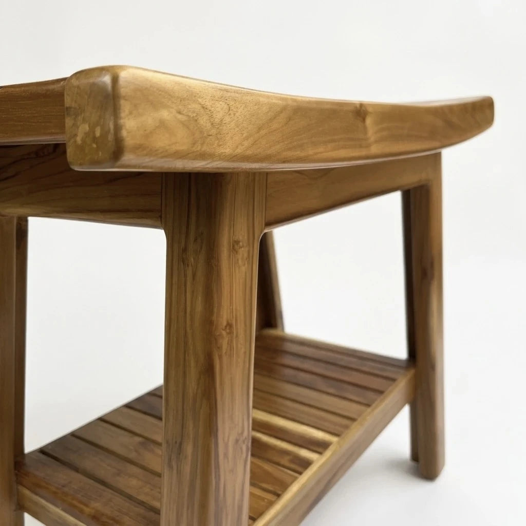 Lower slatted shelf of teak shower bench styled with shampoo bottles and folded towels
