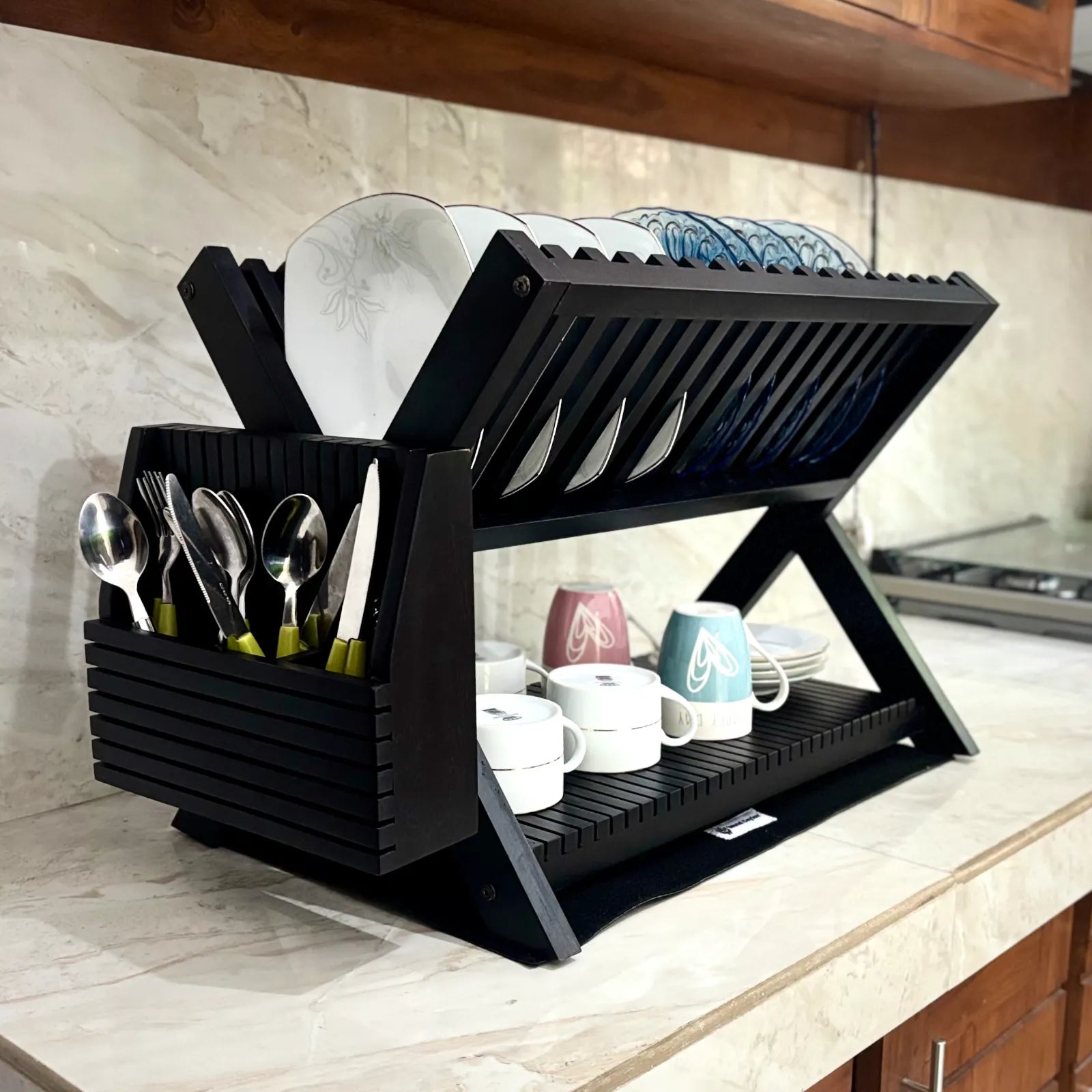 Wood Ceylon black wooden dish drying rack with two tiers holding plates, cups, and utensils on a kitchen counter