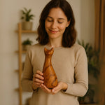 Woman holding a wooden cat sculpture carved with smooth curves and a smiling face