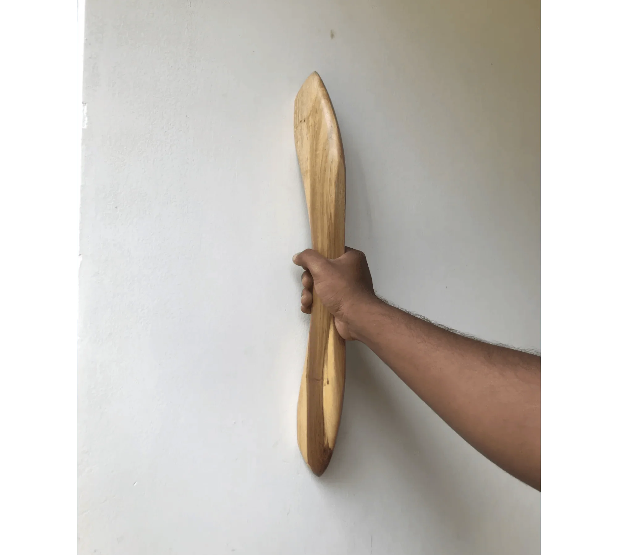 Hand holding a wooden closet door handle with a sleek design against a white background
