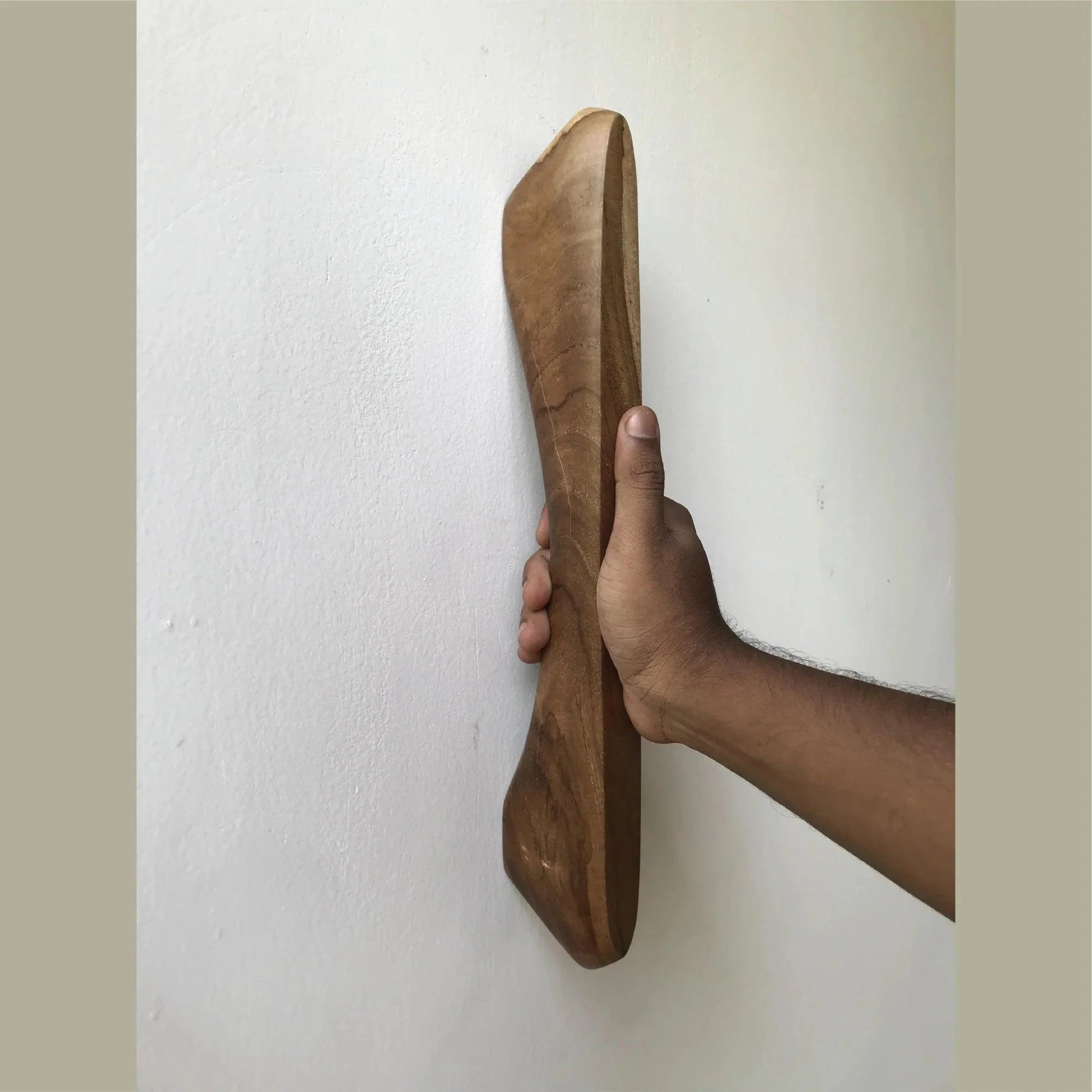 Hand holding wooden Front Door Handle Hardware by Wood Ceylon mounted on a white wall