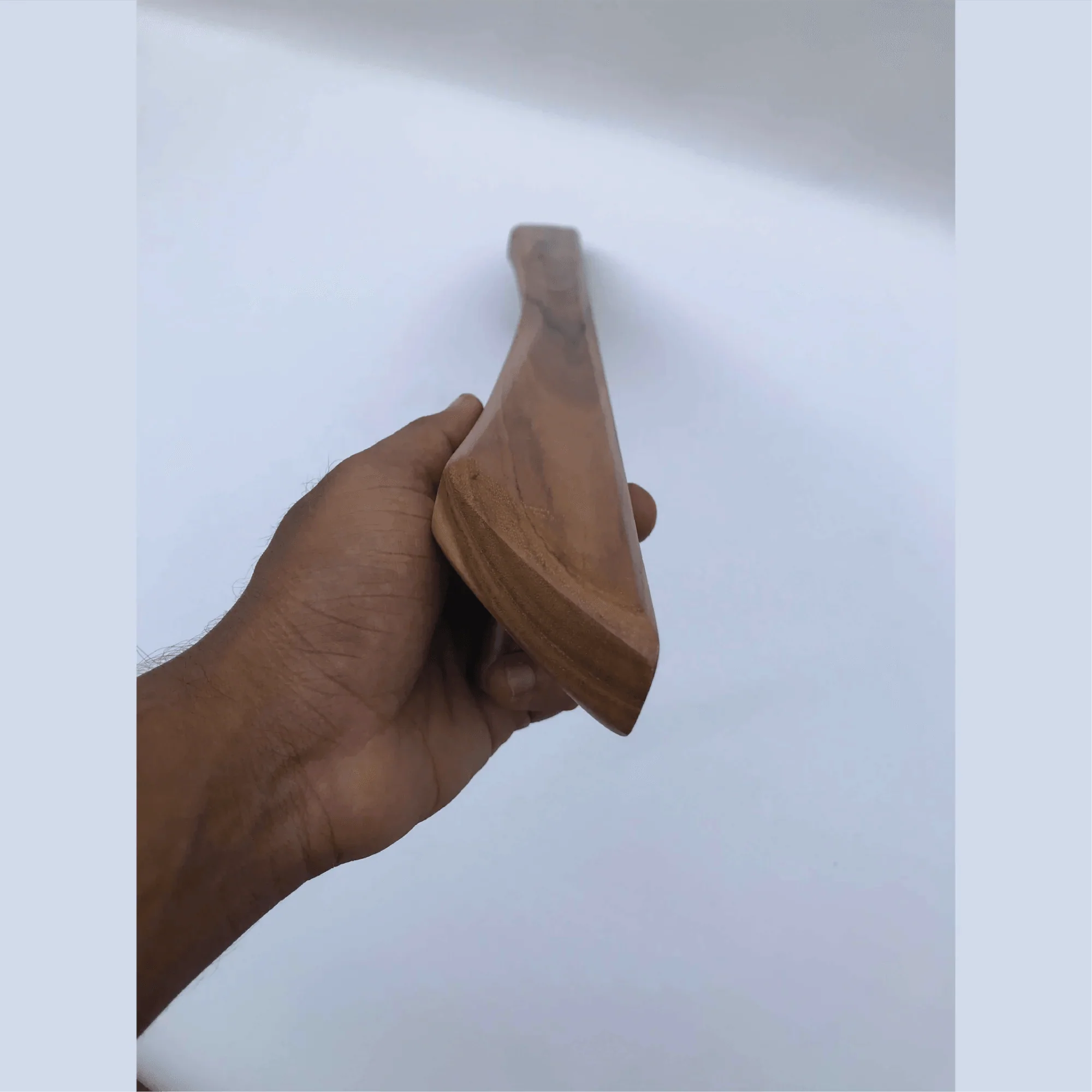 Hand holding a sleek wooden Handmade Barn Door Handles by Wood Ceylon against a plain background