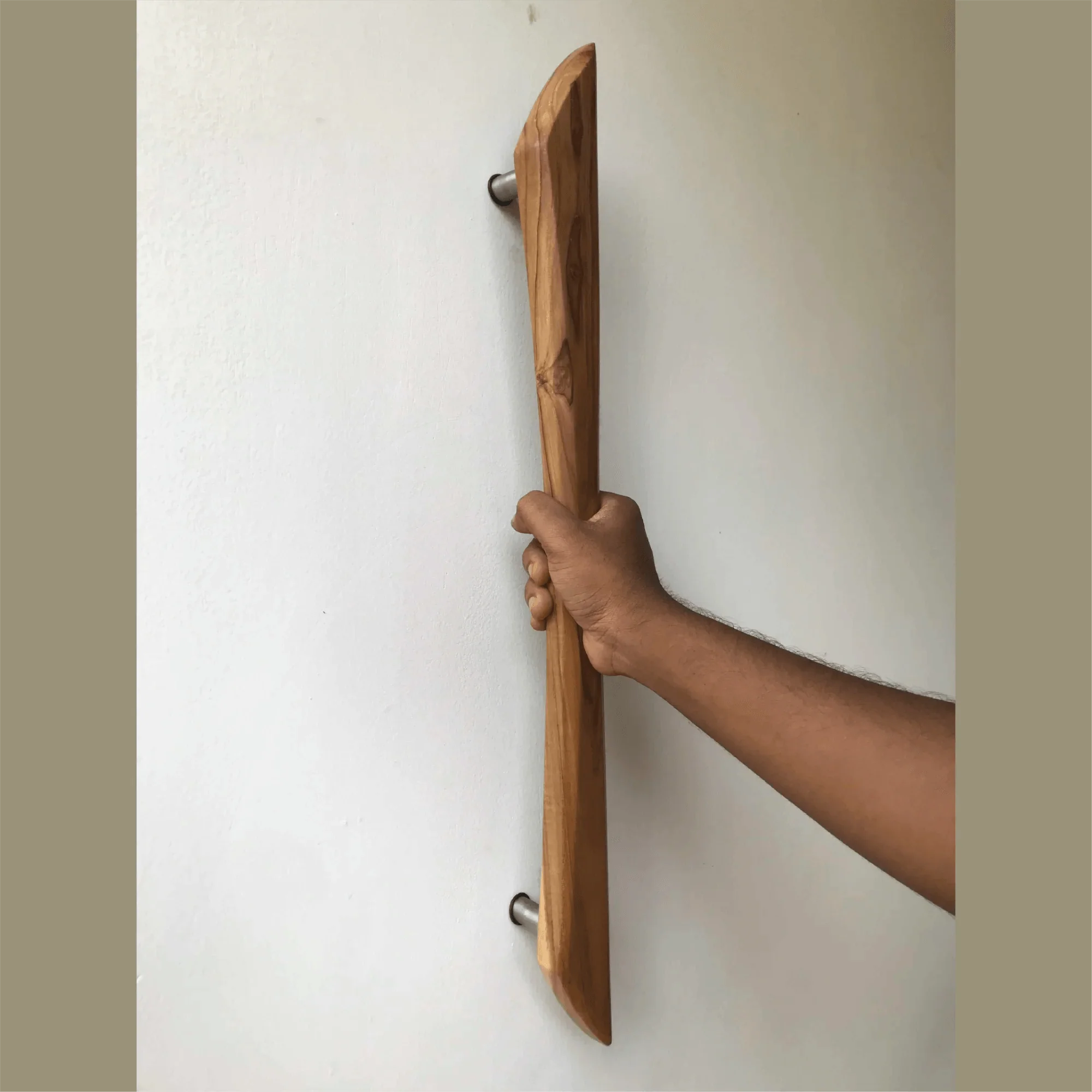Hand holding a wooden door handle installed on white wall featuring Handmade Barn Door Handles