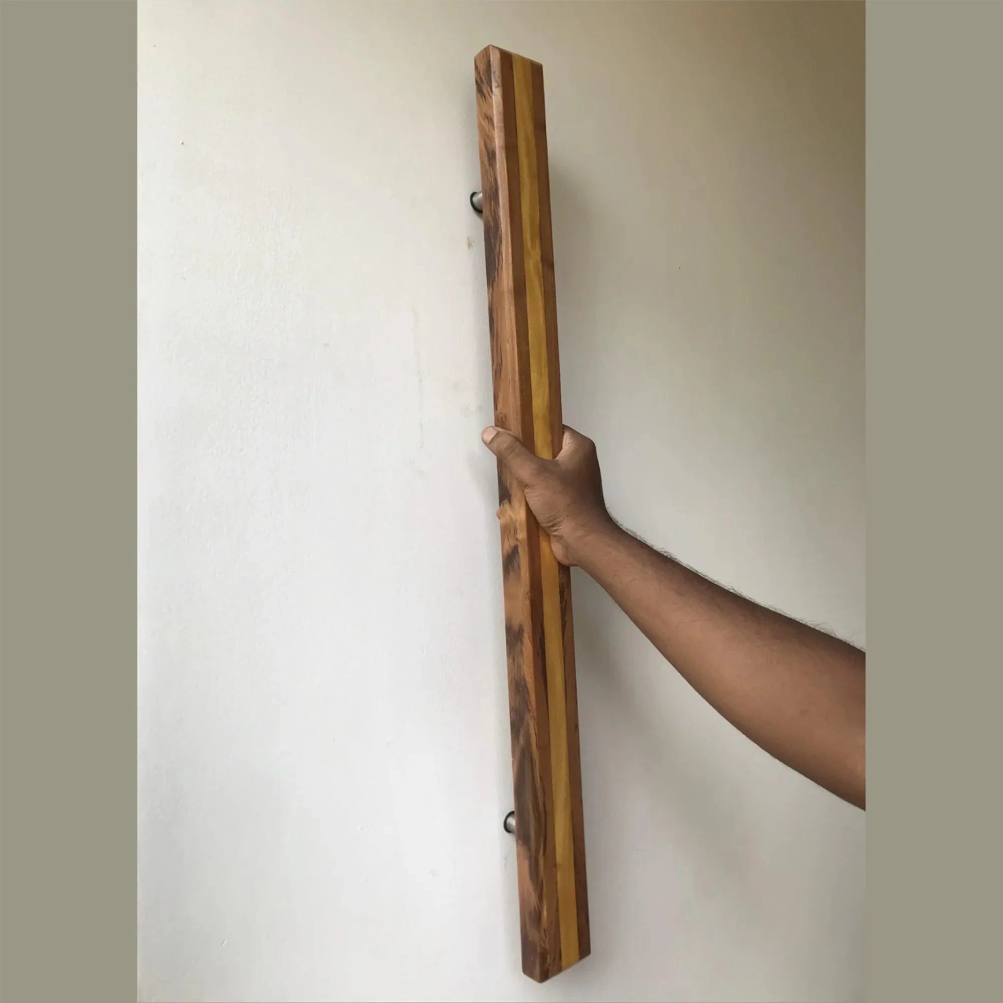Hand holding a large wooden door handle made from mixed wood tones by Wood Ceylon