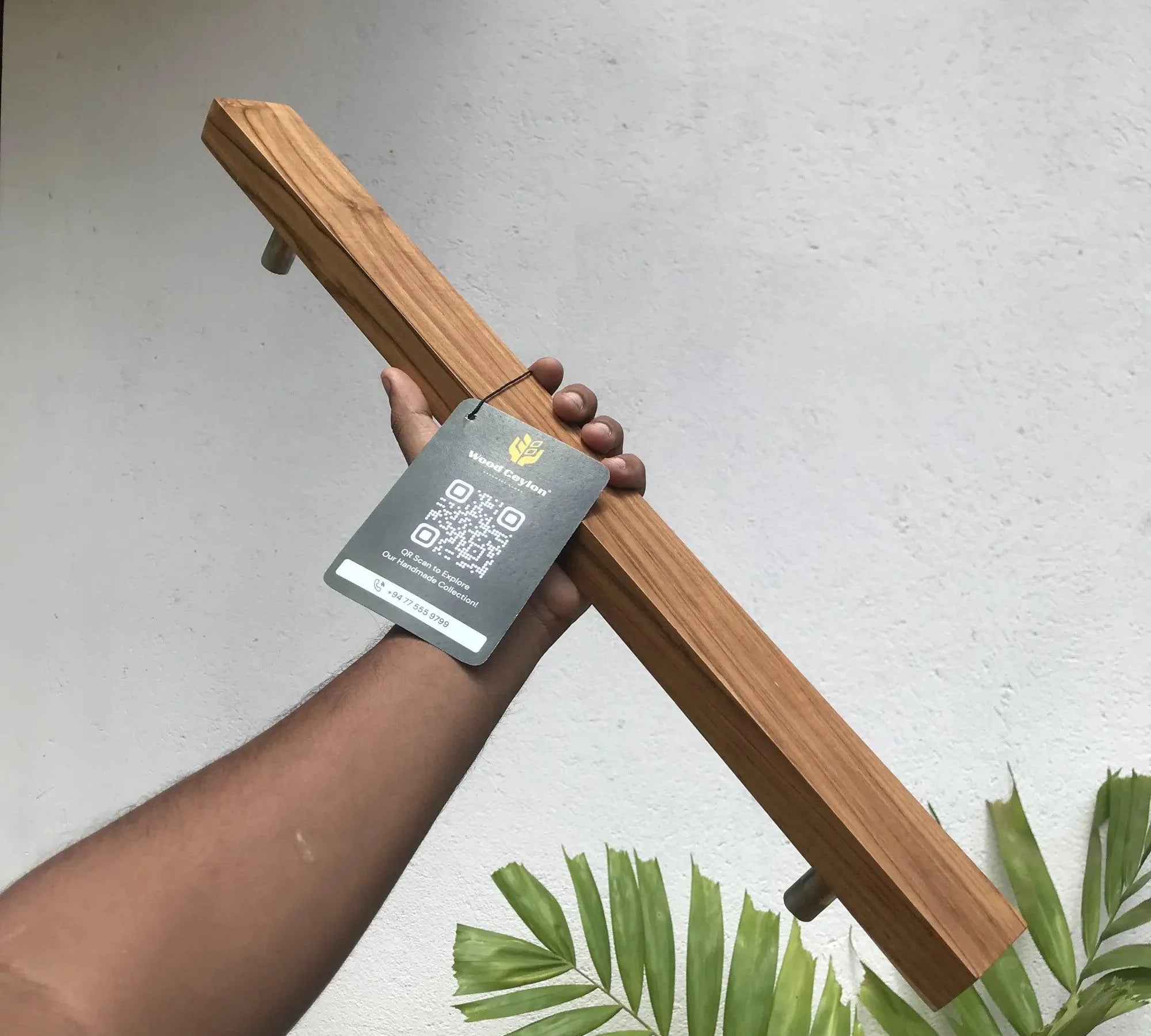 Hand holding a solid teak door handle with a sleek design and modern finish