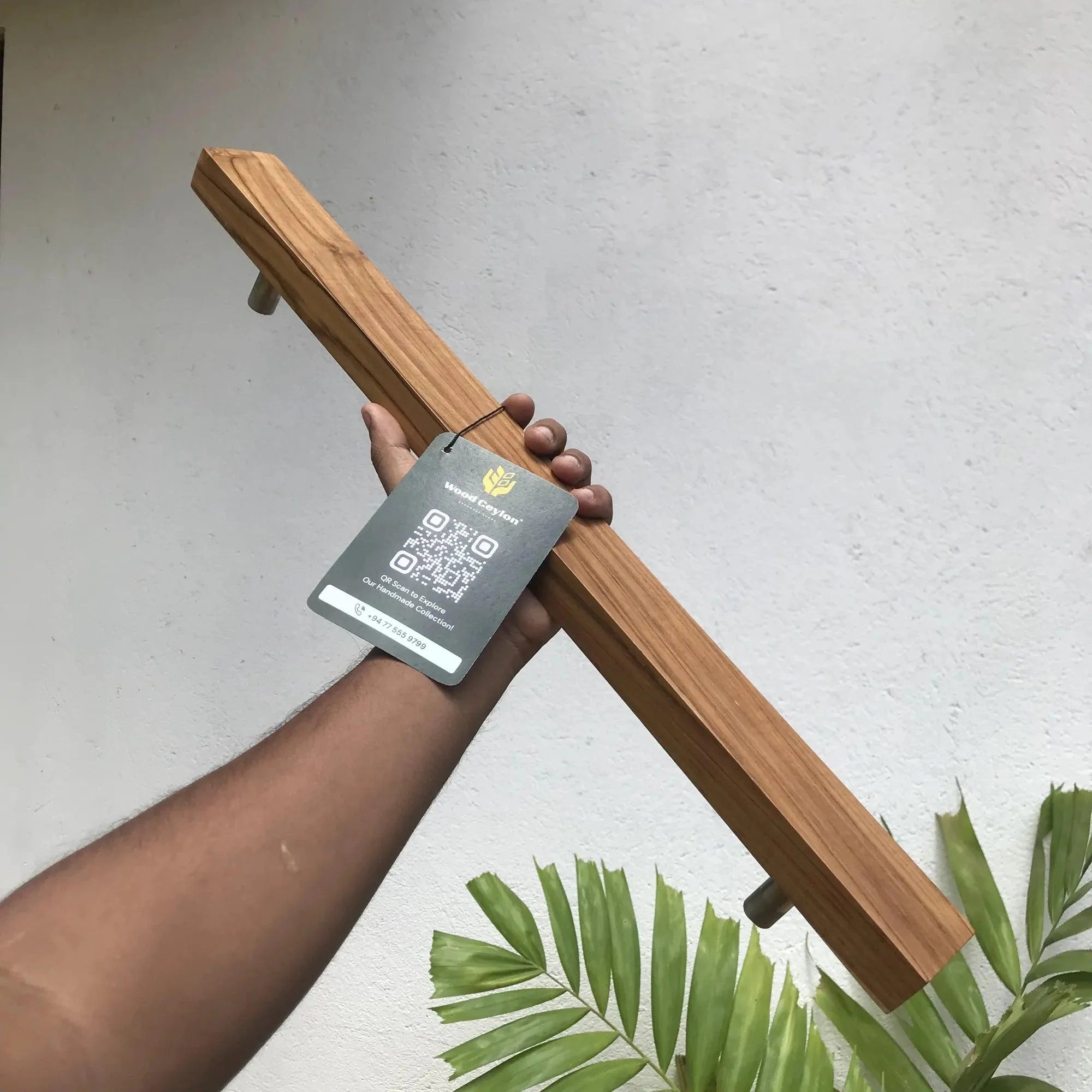 Hand holding a solid teak door handle with a sleek design and modern finish