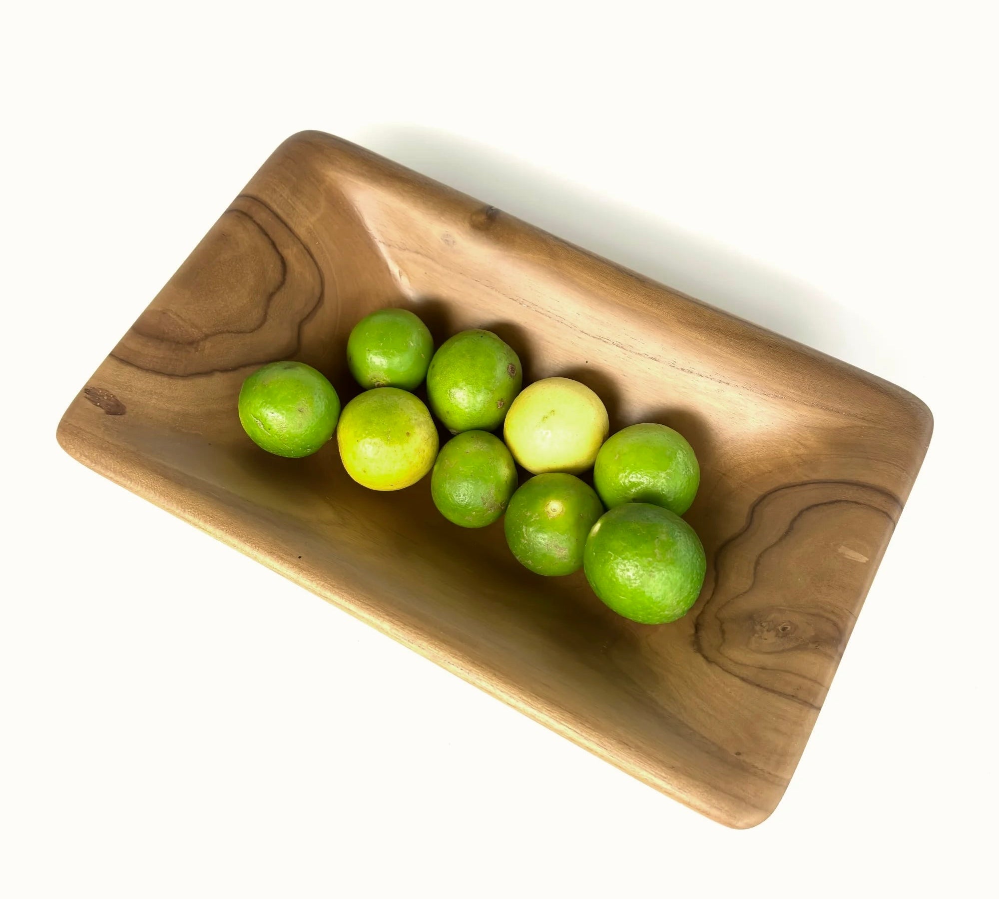 Teak wood serving bowl by Wood Ceylon filled with fresh green limes for modern dining