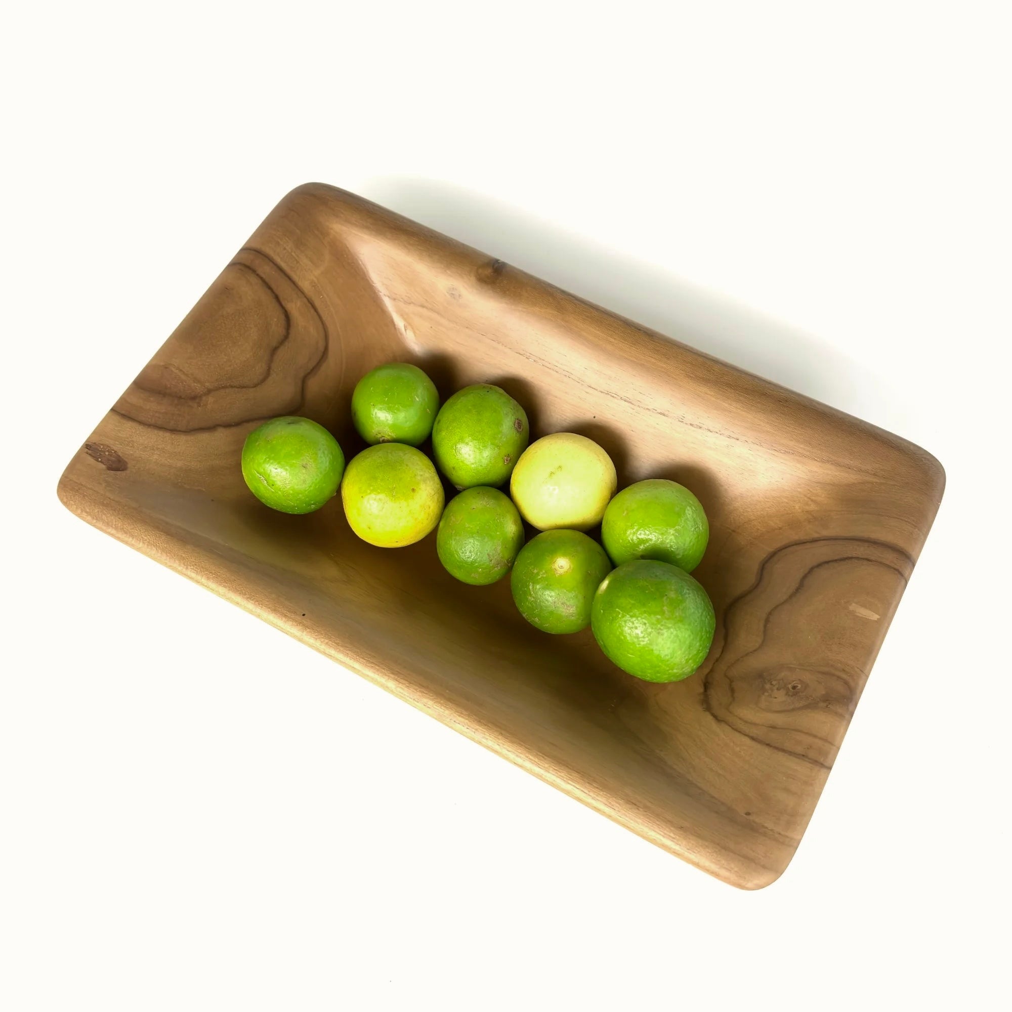 Teak wood serving bowl by Wood Ceylon filled with fresh green limes for modern dining