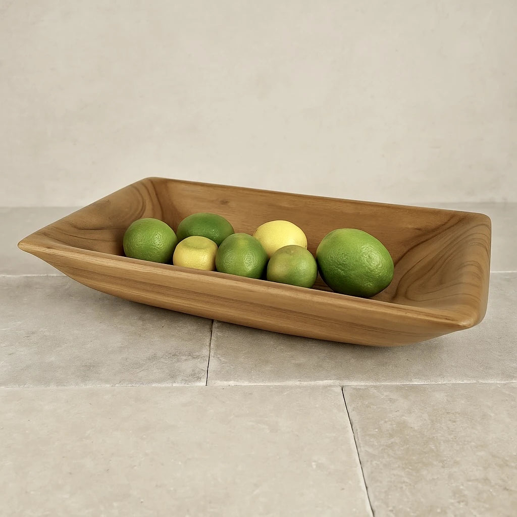Elegant teak wood serving bowl filled with fresh limes and lemons on a stone countertop