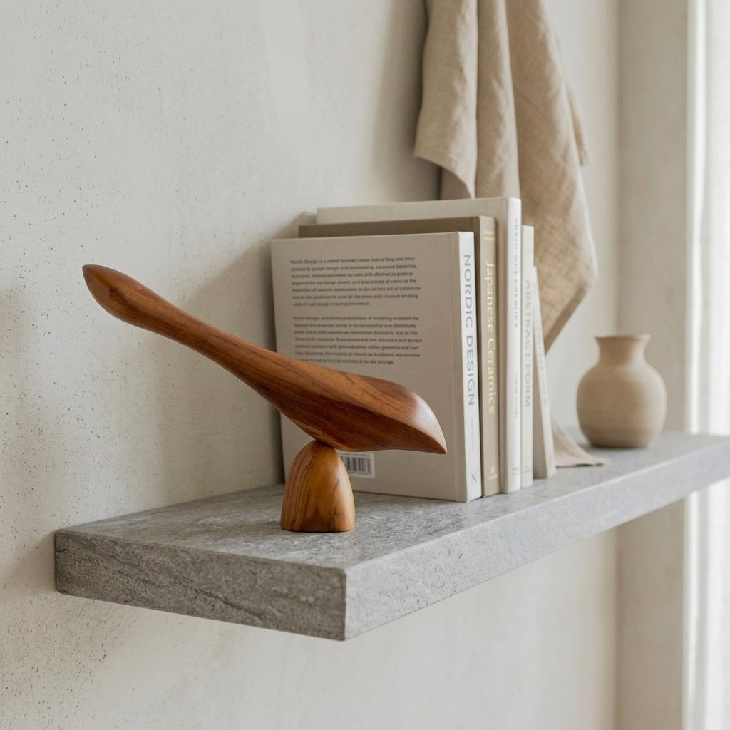 Teak wood bird sculpture elegantly displayed on a concrete shelf