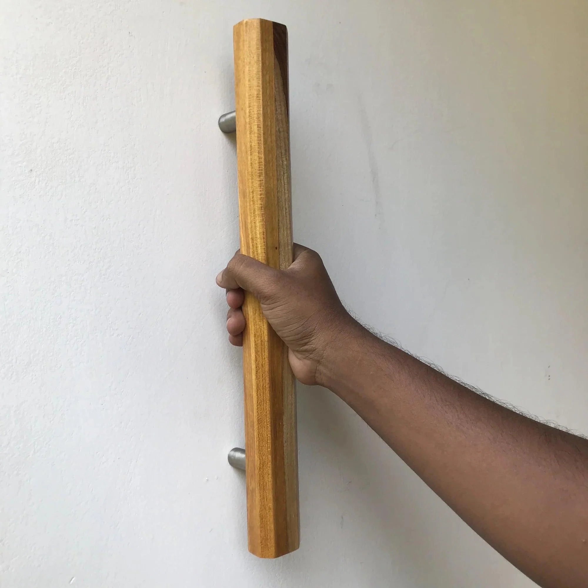 Natural wood barn door handle in hand showcasing rustic design and sturdy grip for doors