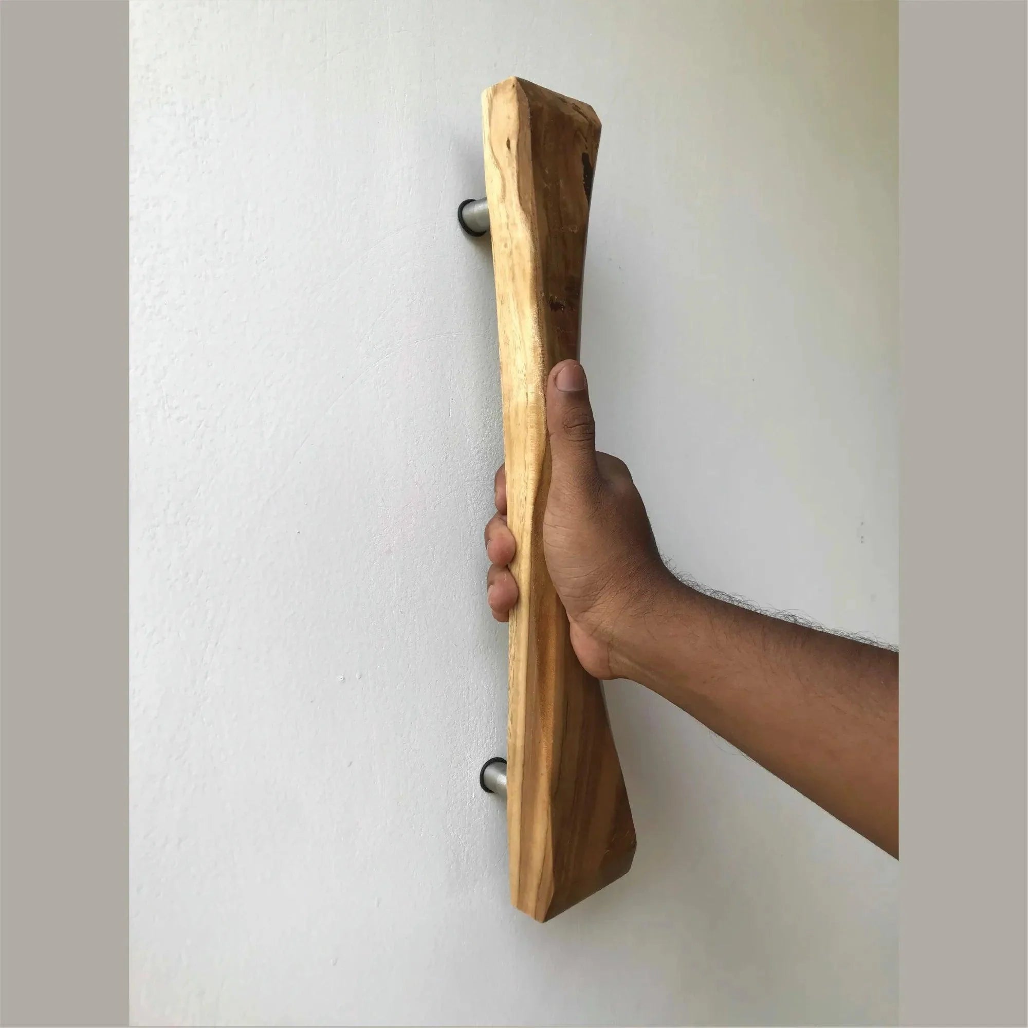 Wooden sliding door handle being held by a hand mounted on a white wall by Wood Ceylon