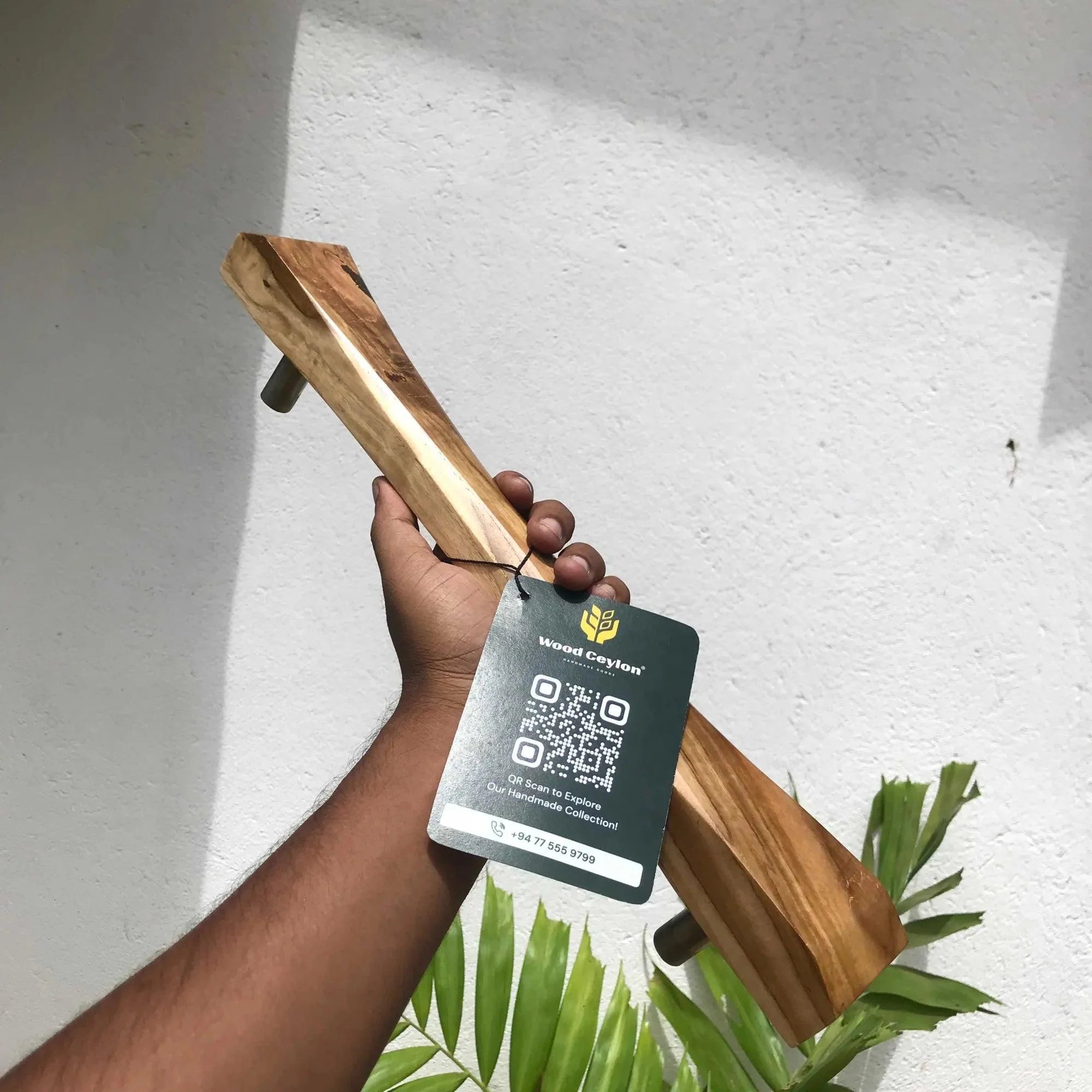 Hand holding Wood Ceylon wooden sliding door handle with natural finish and product tag