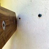 Installation view of a wooden key holder with shelf showcasing mounting holes on a wall