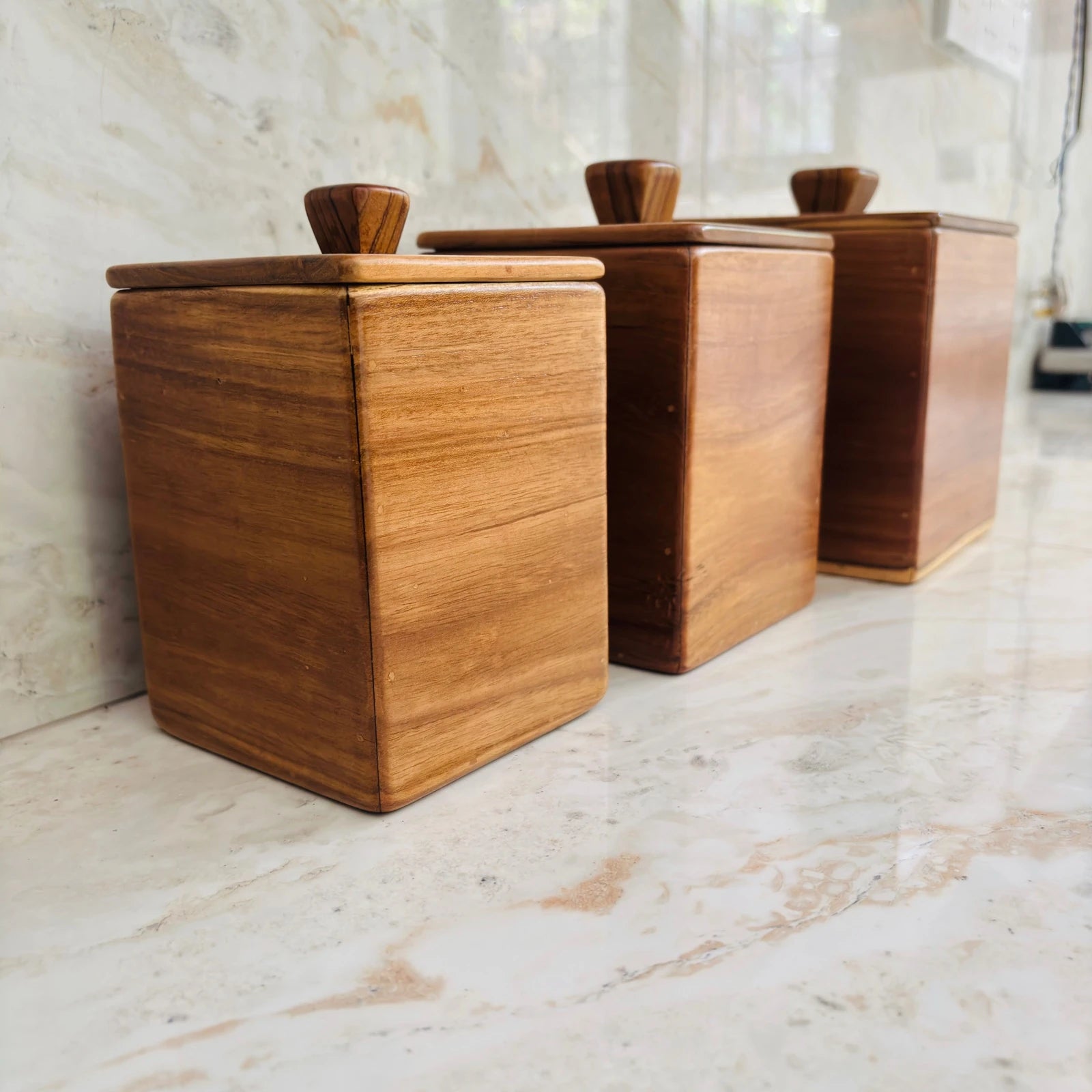 Wood Ceylon kitchen canister set of 3 made of smooth natural wood with lids on marble countertop